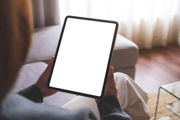 istock Mockup image of a woman holding digital tablet with blank desktop screen while sitting on a sofa at home 1740544000