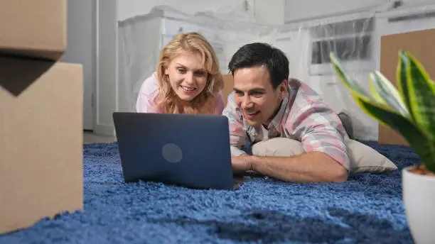 Photo of Happy family use laptop macbook. Couple choose new furniture on computer concept