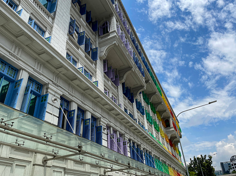 Hill Street, Downtown Core, Singapore - February, 10 2023: Stock photo showing view of the MICA Building (Ministry of Information Culture and the Arts) the former Old Hill Street Police Station with window frames and shutters painted to form the rainbow spectrum.