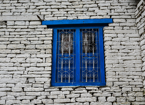 Blue wooden window with brick wall of rural house in Nepal.