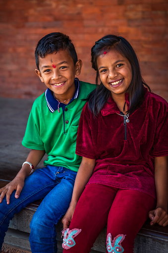 Happy children sitting  in Durbar Square of Bhaktapur. Bhaktapur is an ancient town in the Kathmandu Valley and is listed as a World Heritage Site by UNESCO for its rich culture, temples, and wood, metal and stone artwork.