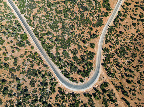 Asphalt road covered with maquis plants.Mediterranean region.Aerial drone shooting.Bird's eye view view of winding, winding, rural road