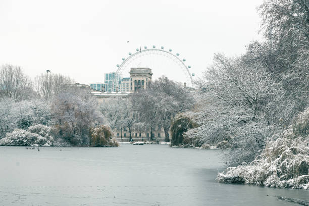 Enchanting London Winter View from St. James's Park, Westminster A mesmerizing winter scene in London as the Horse Guards building stands majestically near a frozen lake in St. James's Park, Westminster. The city is covered in a blanket of snow, creating a truly magical and fairy-tale-like atmosphere. winter wonderland london stock pictures, royalty-free photos & images