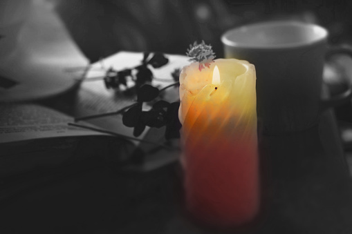Candlelight in the dark, flowers, book. Mourning. Burning candle. Sorrow