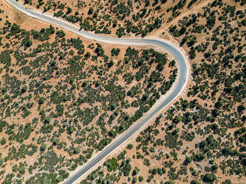 Asphalt road covered with maquis plants.Mediterranean region.Aerial drone shooting.Bird's eye view view of winding, winding, rural road