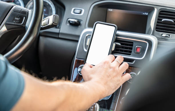 istock Man driving a car and using smartphone with blank white screen on the dashboard 1740604112