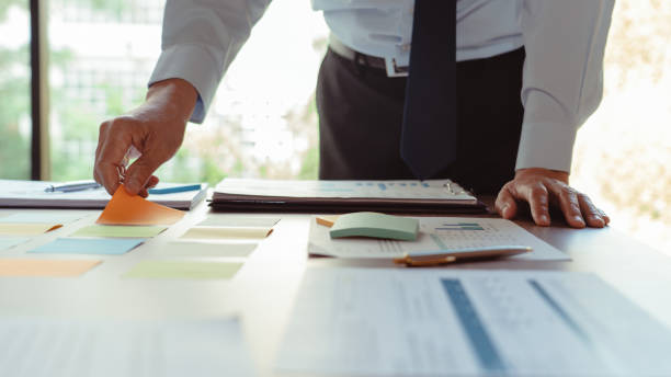 istock Senior businessman putting sticky notes on table to share ideas and data about strategy of business 1740625769