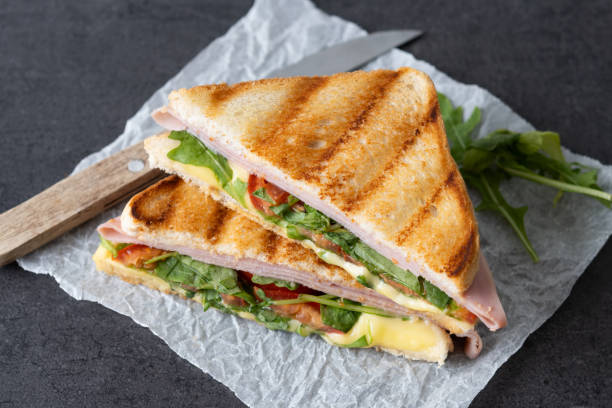 istock Panini sandwich with ham, cheese, tomato and arugula on black slate background 1740628748
