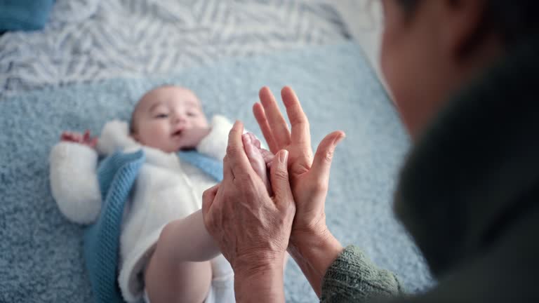 Baby feet, hands and massage lotion for legs with a person at family home with love, care and support together. Bed, foot and happy young kid in a house with skin cream for newborn in a bedroom