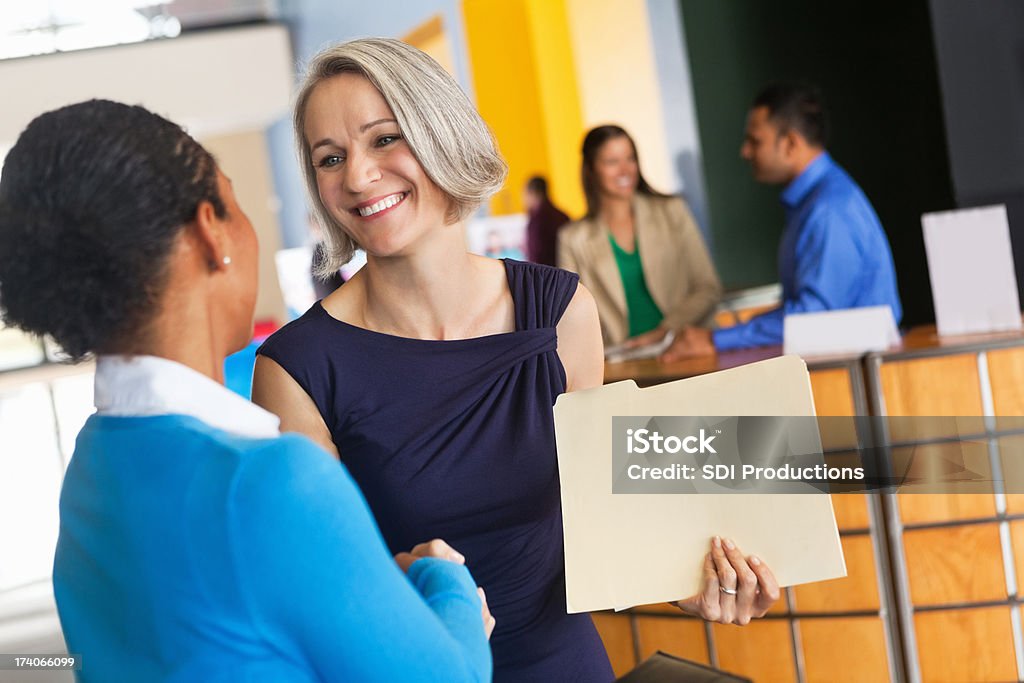 Mature businesswoman shaking hands with prospective employee at job fair Job Fair Stock Photo
