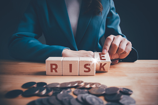 Businesswoman hand flipping wooden blocks cubes text between RISE and RISK on table. Risks assessment. Business risk management and growth performance. Planning strategies and achieving goals.