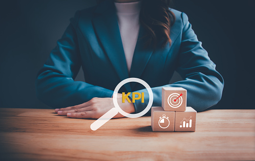 Businesswoman with KPI text on wooden blocks. KPI, Key Performance Indicator. Business goals, performance results and indicators, business planning and measure success, target achievement concept.