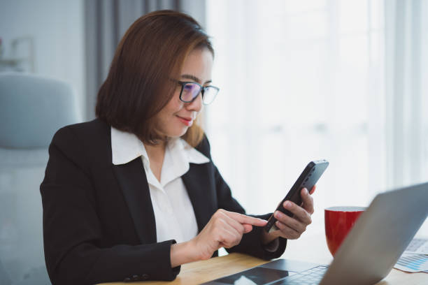 istock Businesswoman using smartphone after working with laptop on table, woman using mobile phone search or social media or shopping online or stock or crypto currency. Smart phone conversation conferrence. 1740699892