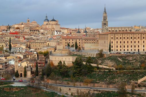 Toledo, Spain - December 07, 2021: Photo of a view of the buildings of the historic part of the city with numerous churches and the Cathedral against a stormy sky in the city of Toledo, near Madrid