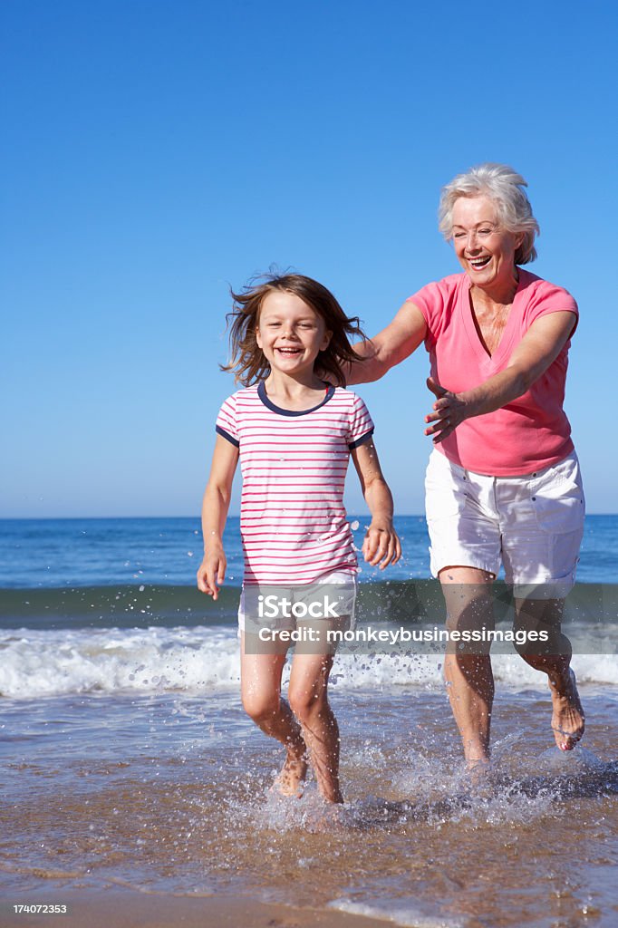 Grandmother Chasing Granddaughter Along Beach Grandmother Chasing Granddaughter Along Beach Out of Sea. Beach Stock Photo