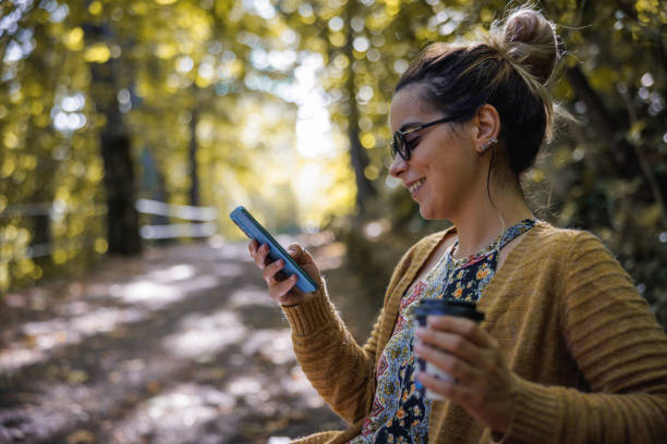 istock Smiling woman text messaging in public park 1740725899