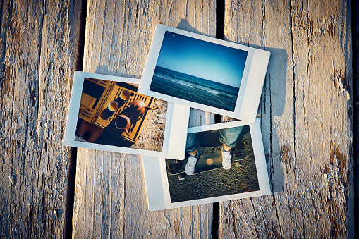 A several instant photographs lie on a old wooden table.