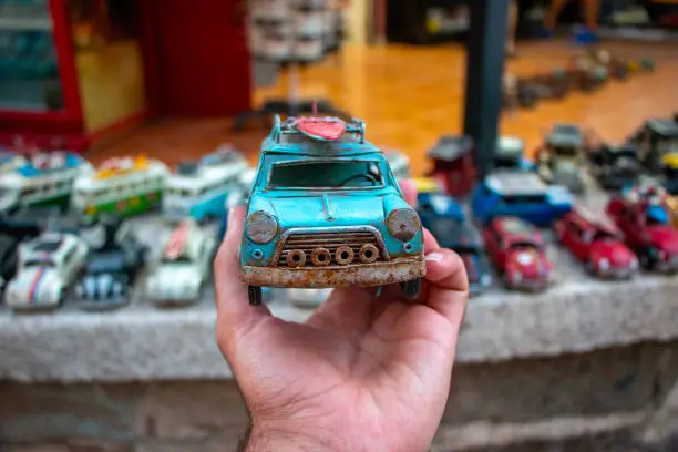 Photo of Volkswagen Beetle in a store selling toy car models. Man is holding the car in his hand.Old model blue color car model. Old retro car.