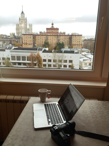 Moscow, Russia - Oct 4, 2016. A Macbook with digital camera on table with cityscape background.