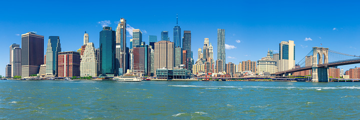 Stitched Panorama of Manhattan Lower East Side Financial District, Brooklyn Bridge, World Trade Center, Blue Sky with Clouds and Water of East River, New York, USA. Canon EOS 6D (Full Frame censor) DSLR and Canon EF 24-105mm f/4L lens. 3:1 Image Aspect Ratio.