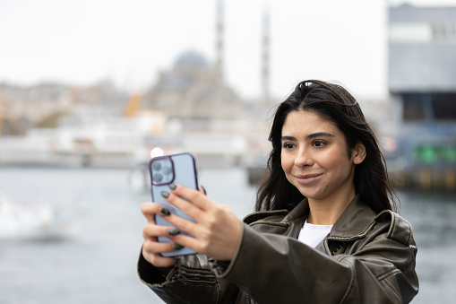 Pretty young lady is taking a selfie with Istanbul cityscape.