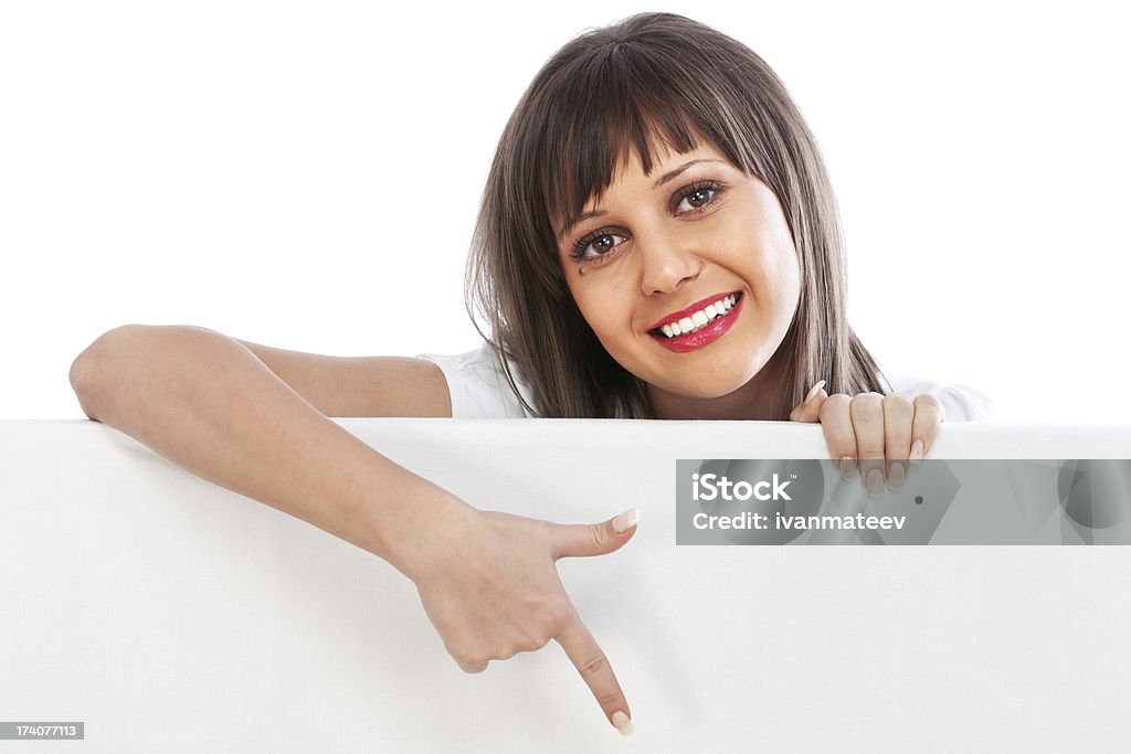 Young woman pointing behind billboard Young woman pointing behind white billboard isolated on white background Adult Stock Photo