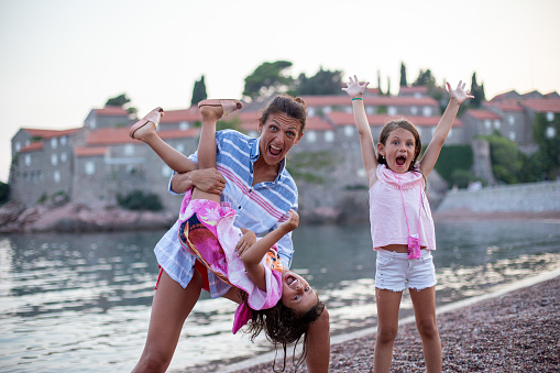 Posing fashionable mom with two fashion daughters take fun in Montenegro on island Saint Stefan