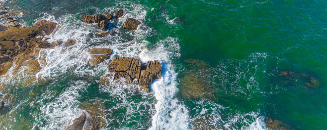 aerial view of a rocky coastline and the foam of the waves