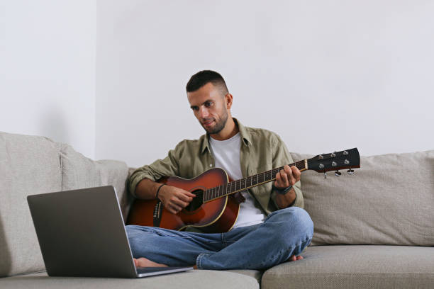 istock Mid adult guy Practicing guitar playing at home. 1740788038