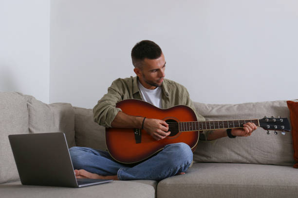 istock Mid adult guy Practicing guitar playing at home. 1740788078