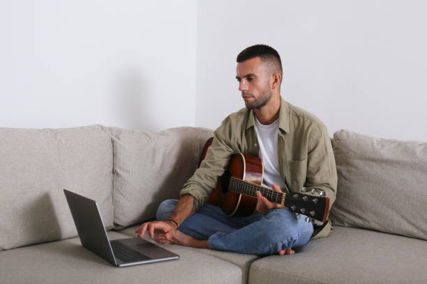 istock Mid adult guy Practicing guitar playing at home. 1740789217
