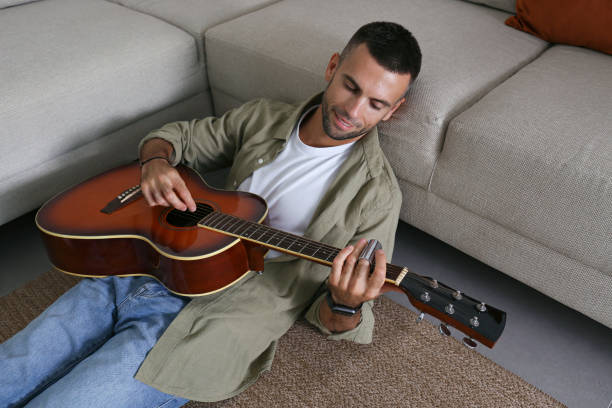 istock Mid adult guy Practicing guitar playing at home. 1740789890