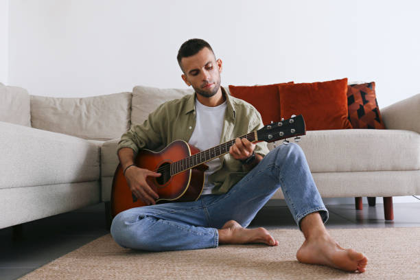 istock Mid adult guy Practicing guitar playing at home. 1740789902