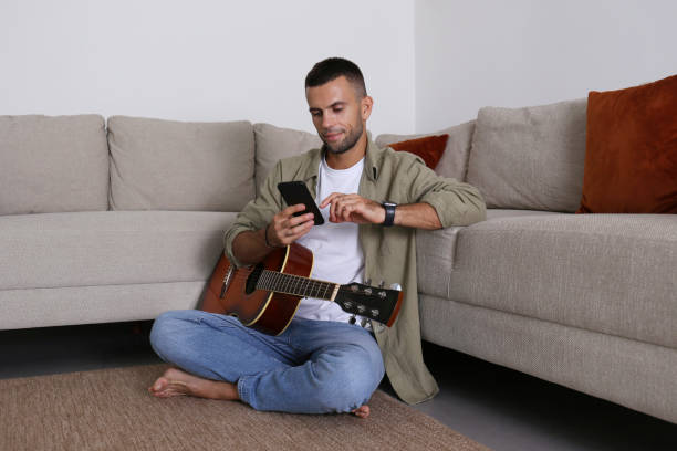 Mid adult guy Practicing guitar playing at home.
