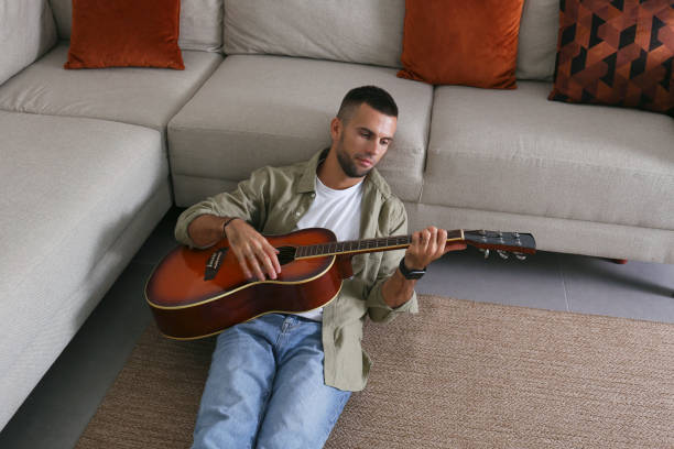 istock Mid adult guy Practicing guitar playing at home. 1740791017
