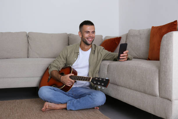 istock Mid adult guy Practicing guitar playing at home. 1740793967