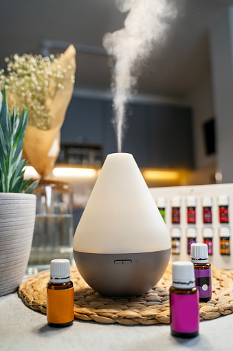 Air diffusor standing on kitchen table, air purification concept, essential oils in bottles next to it
