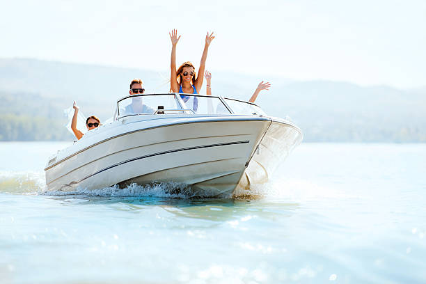 joyeux jeunes équitation dans un hors-bord. - motorboat nautical vessel speedboat lake photos et images de collection