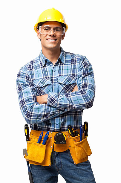 Young Construction Worker - Isolated Portrait of happy young construction worker with tool belt standing arms crossed. Vertical shot. Isolated on white. tool belt stock pictures, royalty-free photos & images