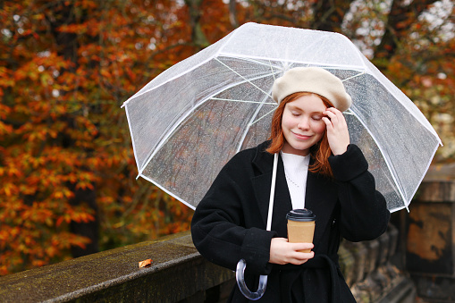 Girl rain umbrella. Happy girl prepare hair with transparent umbrella outdoors with cup of coffee.