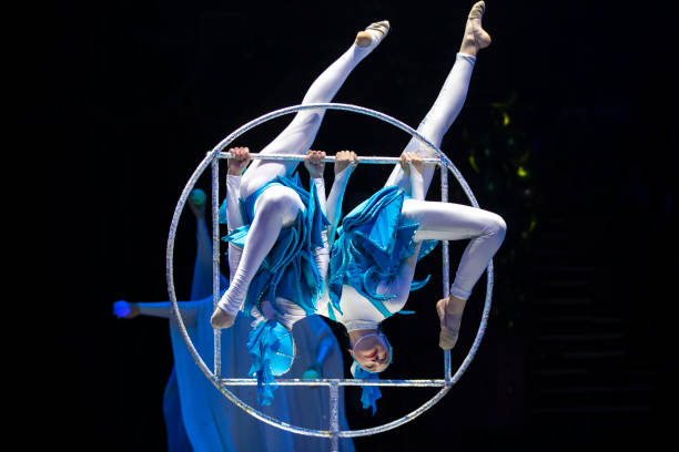 istock Two acrobat girls show a circus number on a dark background. Acrobatic performance. 1740823074