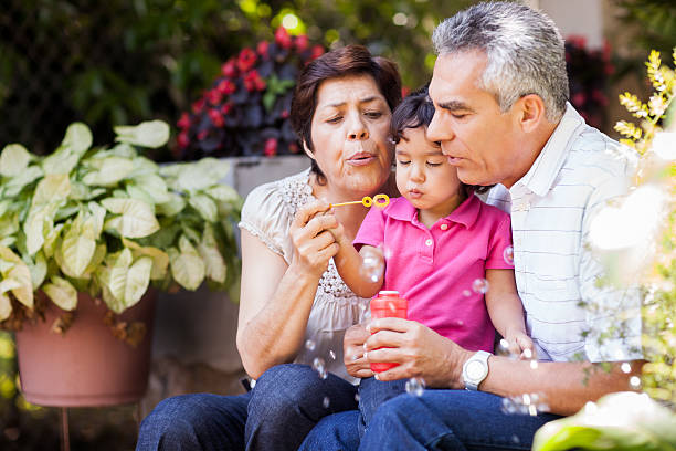 Grandparents and granddaughter making bubbles Grandparents and granddaughter making bubbles hispanic grandmother stock pictures, royalty-free photos & images