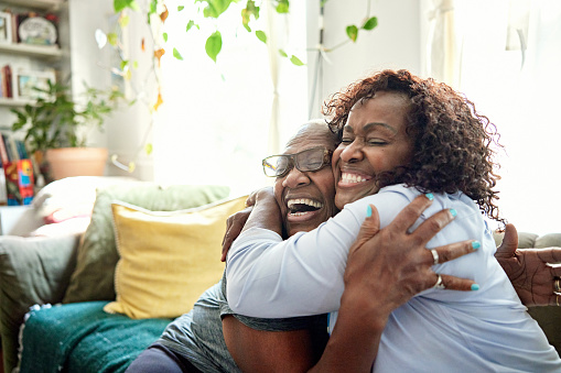 Madre negra e hija adulta abrazándose y riendo photo