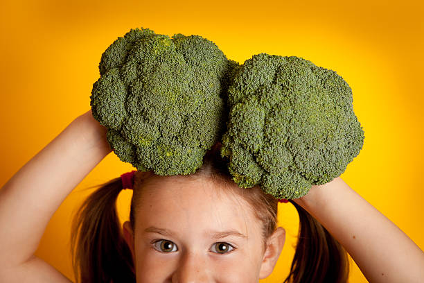 istock Little Girl Holding Broccoli On Her Head 174082971