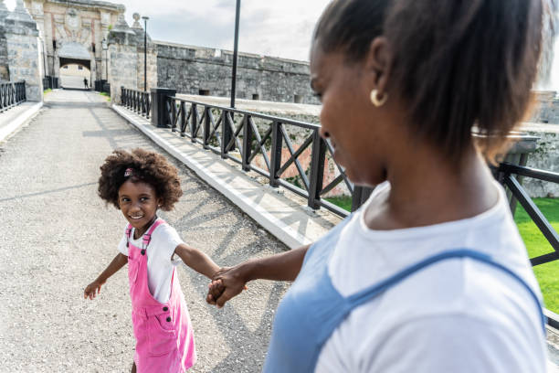 Child girl walking on the bridge with her mother outdoors