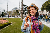 Young Woman Eating A Turkish Bagel In Front Of The Blue Mosque In Istanbul