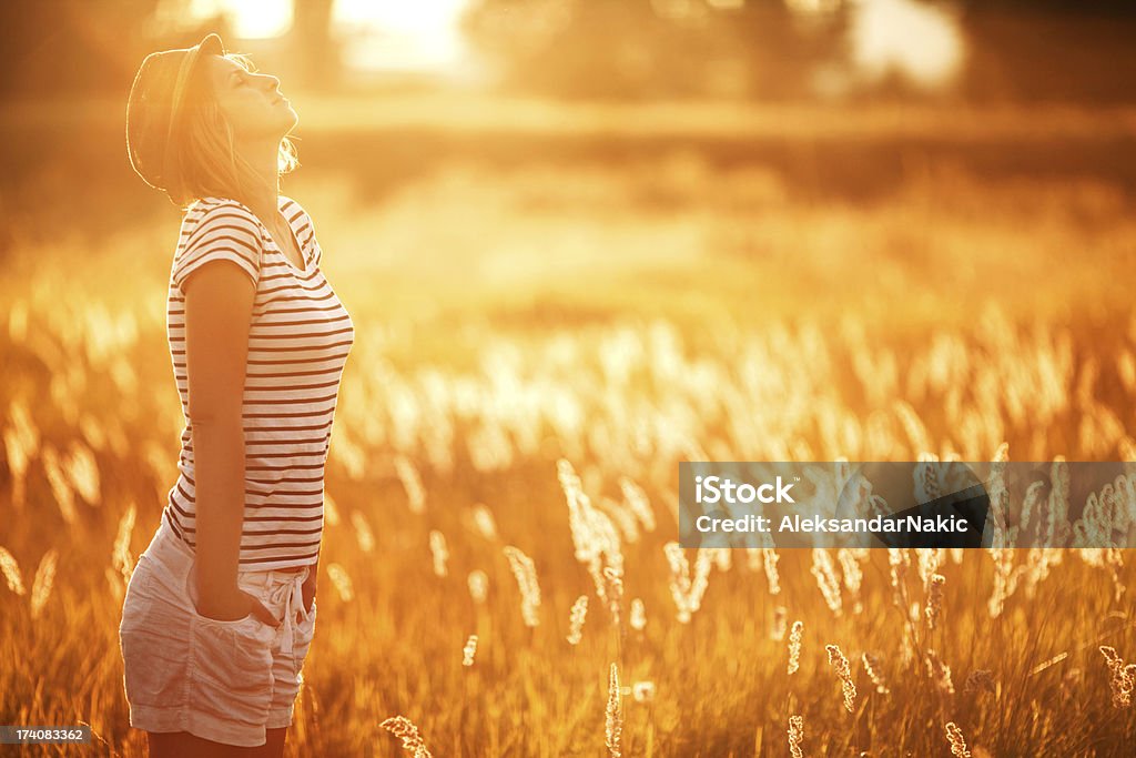 Breathing in Young woman standing on the field on a beautiful sunny day Active Lifestyle Stock Photo