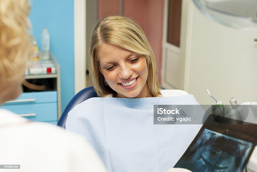 Happy Teenage Girl at dentist office. Portrait of an cute smiling teenage girl having consultations with her dentist at dentist office. Female dentist holding x-ray image and talking with patient. Adolescence Stock Photo