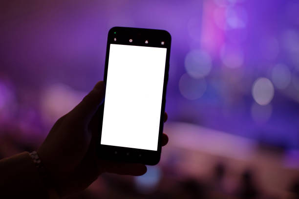 istock A hand holds a smartphone with a blank screen to copy your text or information content on a dark concert bokeh background. 1740844492