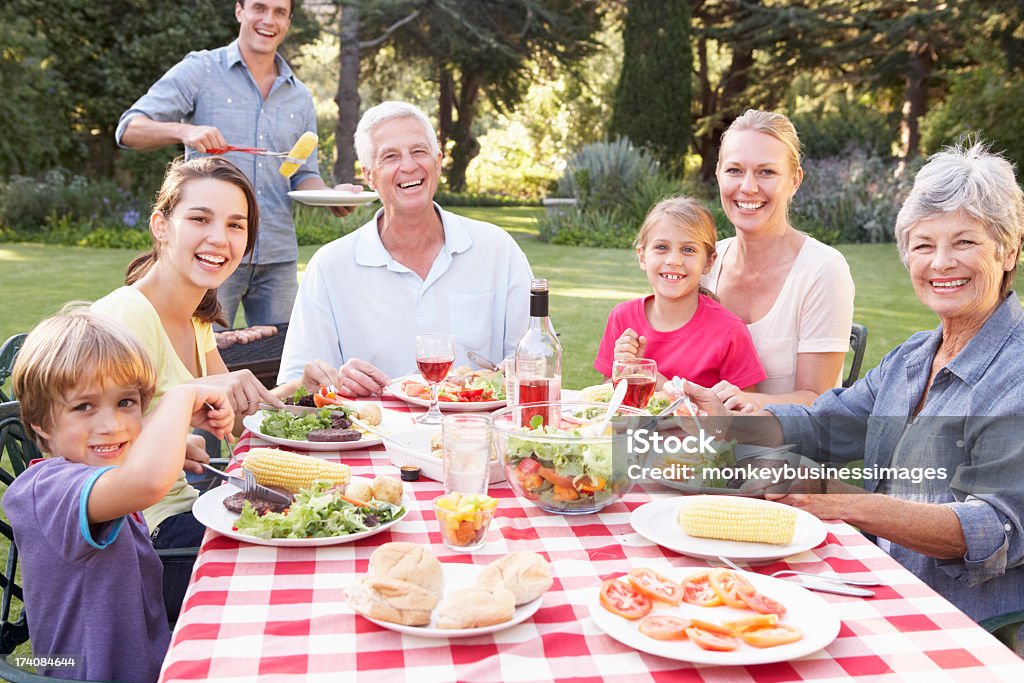 Três gerações de família desfrutando de um churrasco no jardim - Foto de stock de 20 Anos royalty-free